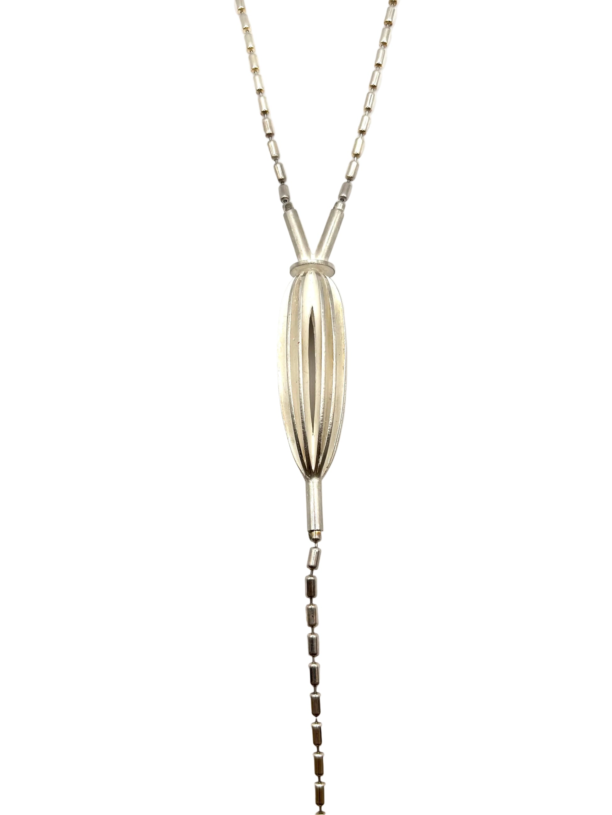 A silver lariat necklace featuring a textured, vertically ribbed teardrop pendant and a delicate chain that extends down the center of the frame, photographed against a plain white background.