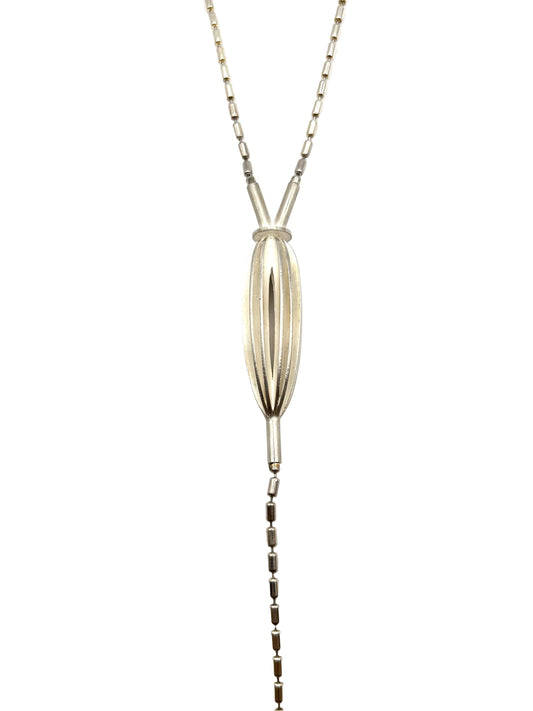 A silver lariat necklace featuring a textured, vertically ribbed teardrop pendant and a delicate chain that extends down the center of the frame, photographed against a plain white background.