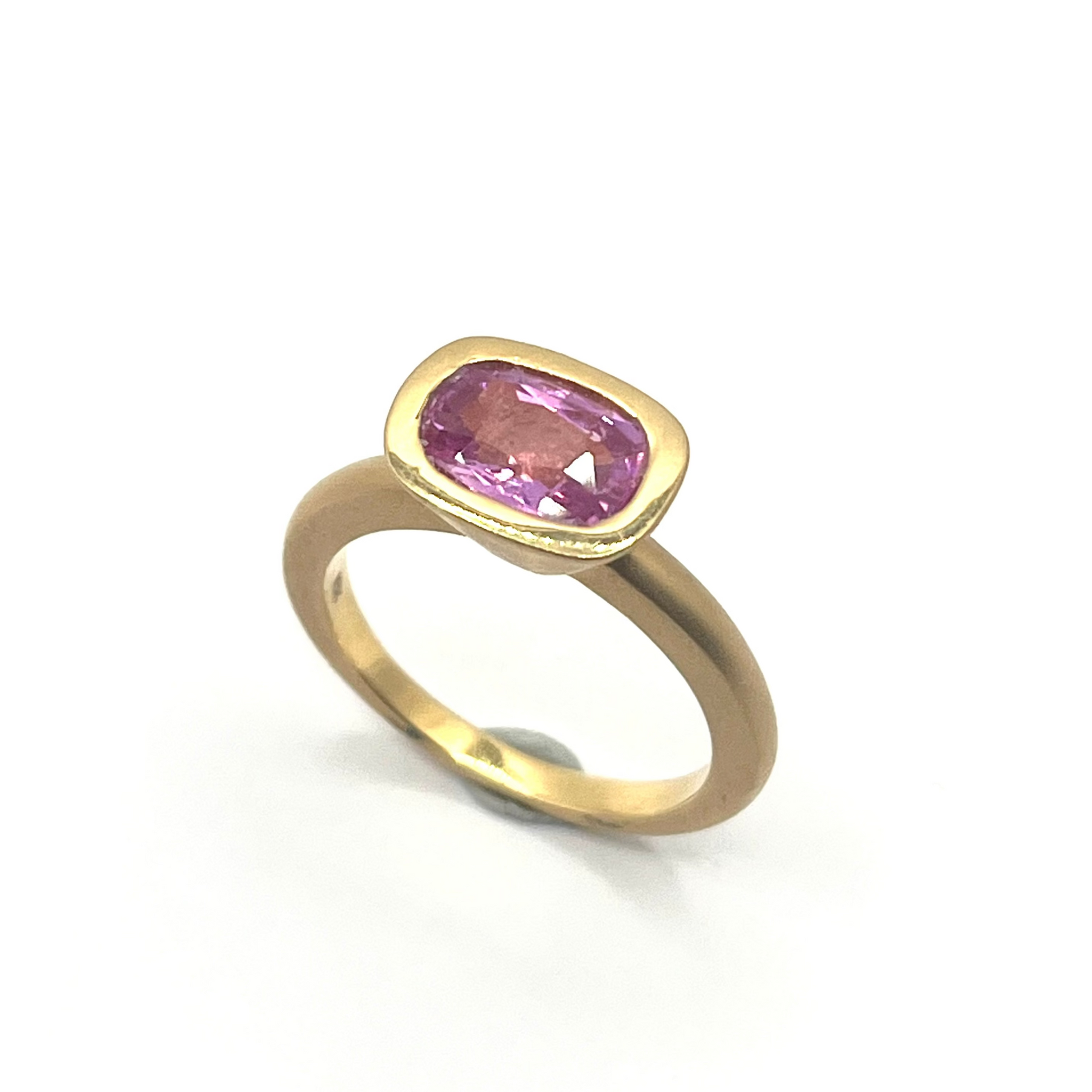 Gold ring with a pink gemstone on a white background
